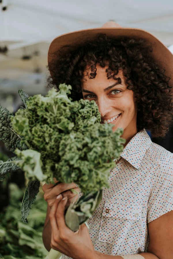 Beautiful woman buying kale at a farmers market